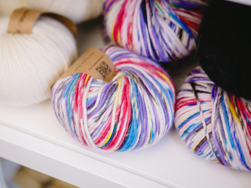 Colourful variegated yarn sits on a white shelf